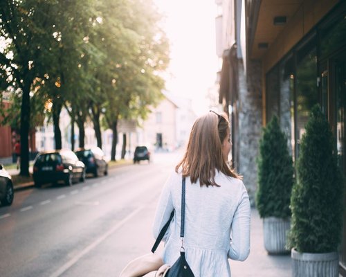 A woman walking on a wide brick sidewalk downtown for fresh air and daily dynamic stepping